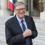Bill Gates Daughter SLAMMED For Bizarre Behavior… A smiling man in business attire standing on steps outside a building
