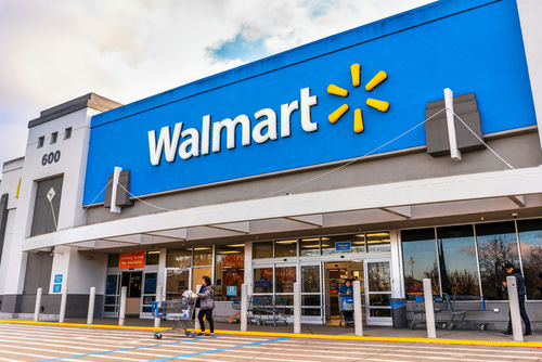 shutterstock_1643463436.jpg Walmart storefront with people and shopping carts outside.