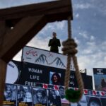 Anti-Racism ICON Caught Funding Neo-Nazis… A protest scene with a speaker and a noose symbolizing oppression
