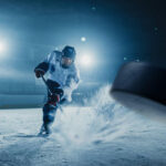 Hockey Legend Found DEAD — Furniture Store Mystery… A hockey player shooting a puck on an ice rink under bright arena lights