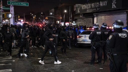 shutterstock_2780071081.jpg Crowd of people gathered on a street with police officers and vehicles