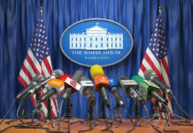 White House Memo Ends War—Or Just Hype? White House podium with multiple microphones and flags.