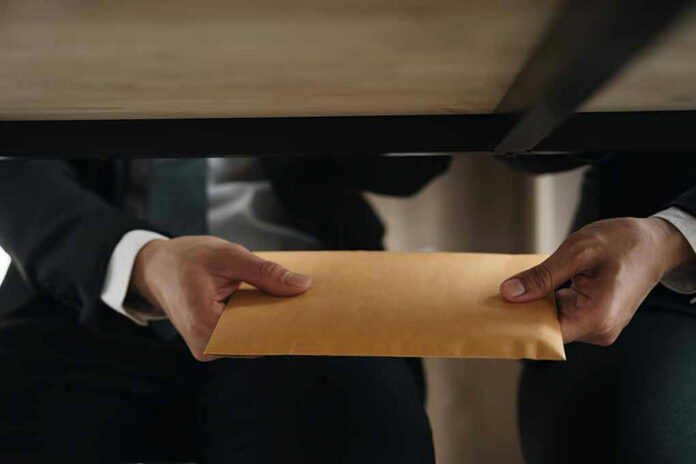 2288891885 Two people exchanging an envelope under a table.