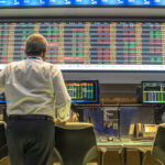 Energy Shock Triggers Korea Freefall Person viewing stock market data on multiple screens.