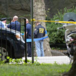 Nuclear Hub Deaths Ignite FBI Probe FBI agents and police officers at a crime scene.