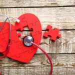 Heart Stops After Swallow? Not So Simple Heart-shaped puzzle and stethoscope on wooden background.