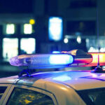 Police Chief Pawns Evidence Gun Police car with flashing lights at night.