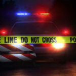 Viral Mugshot Exposes Justice Game Police car behind yellow caution tape at night.