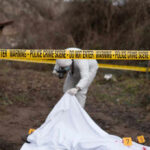 Instructors Charged After Fatal Jump Police crime scene with investigator examining covered body