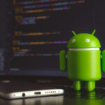 Beijing’s AI Enforcers Go Global? Android figurine in front of a laptop screen.