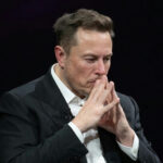 Musk Backing Sparks Right Meltdown Man in suit deep in thought.
