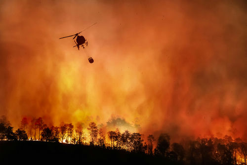 shutterstock_1810018291 Helicopter dropping water on large forest fire.