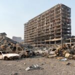 Drone Factory Torched—Ukraine’s DIY Weapon A devastated urban landscape featuring a burnt building and wrecked cars