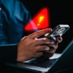 GoFundMe Bombshell Clouds Star’s Death Person holding a smartphone with a notification alert while using a laptop