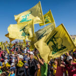Ceasefire Clock Ticks—Hezbollah Stays Mum People waving Hezbollah flags at a large outdoor gathering.