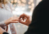 Reality ‘Healing’ Sells While Marriages Sink Groom placing ring on brides finger at wedding.