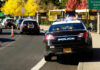 Felon Flees And Ends Up In Governor’s Backyard Police cars and school buses on a sunny street.