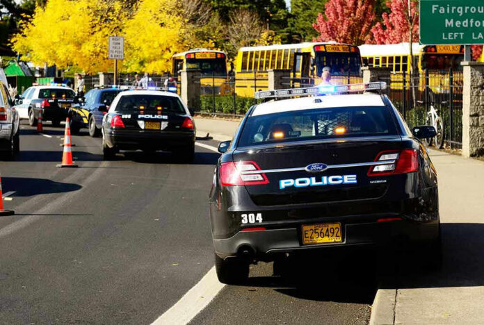 117302929 Police cars and school buses on a sunny street.