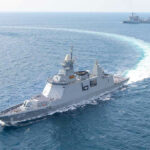 Warships maneuvering at sea, leaving a white wake.
