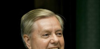 Smiling middle-aged man in a suit speaking at a podium