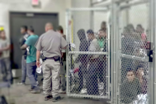shutterstock1229072188-2jpg People detained behind fencing in a detention center.