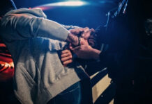Shocking Arrest Clip Ignites Two-Tier Fury Person being handcuffed by an officer beside a police car at night