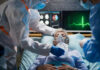 Patient on hospital bed with oxygen mask assisted by healthcare workers