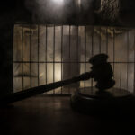 ISIS Plot Hits Suburb—Rabbi Targeted A gavel placed on a wooden surface in front of a barred cage with a smoky background