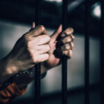 Records Vanish, Dahmer Walks Honorable Hands gripping prison bars, suggesting confinement
