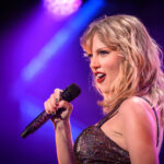 Singer performing on stage with a microphone under colorful lights