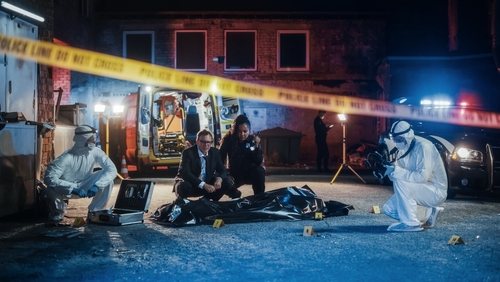 Police and forensic team investigating a crime scene in a dark alley