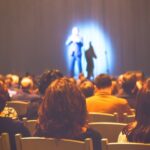Silent Ban Alleged: Fallon Freezes Griffin? Audience watching a performance on stage with dramatic lighting