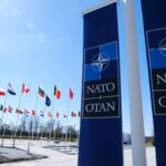 Trump’s Victory Claim Shreds on Impact NATO flags displayed at the headquarters under a clear blue sky