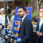 Thermostat Uprising Ignites NYC Man in suit speaks at outdoor press conference with microphones
