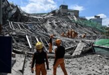 Rescue workers survey collapsed building debris