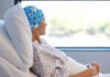 Stunning Switch: Midlife Moms Overtake Teens A female patient in a hospital bed wearing a blue patterned headscarf, looking out a window