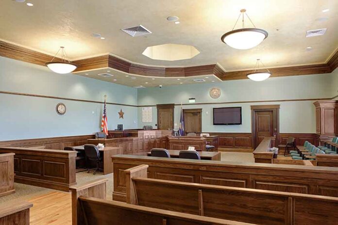 Empty courtroom with wooden benches and desks.