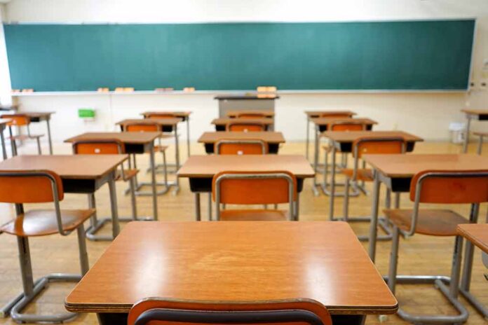 Empty classroom with wooden desks and chalkboard.