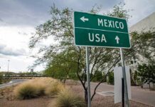 Direction sign for Mexico left, USA straight ahead.