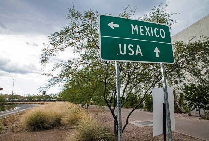 Direction sign for Mexico left, USA straight ahead.