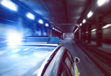 Police car speeding through a tunnel with lights flashing.