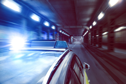 Police car speeding through a tunnel with lights flashing.