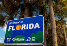 Welcome to Florida sign with palm trees background.